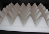 close up picture of white acoustic foam panel with pyramid style front